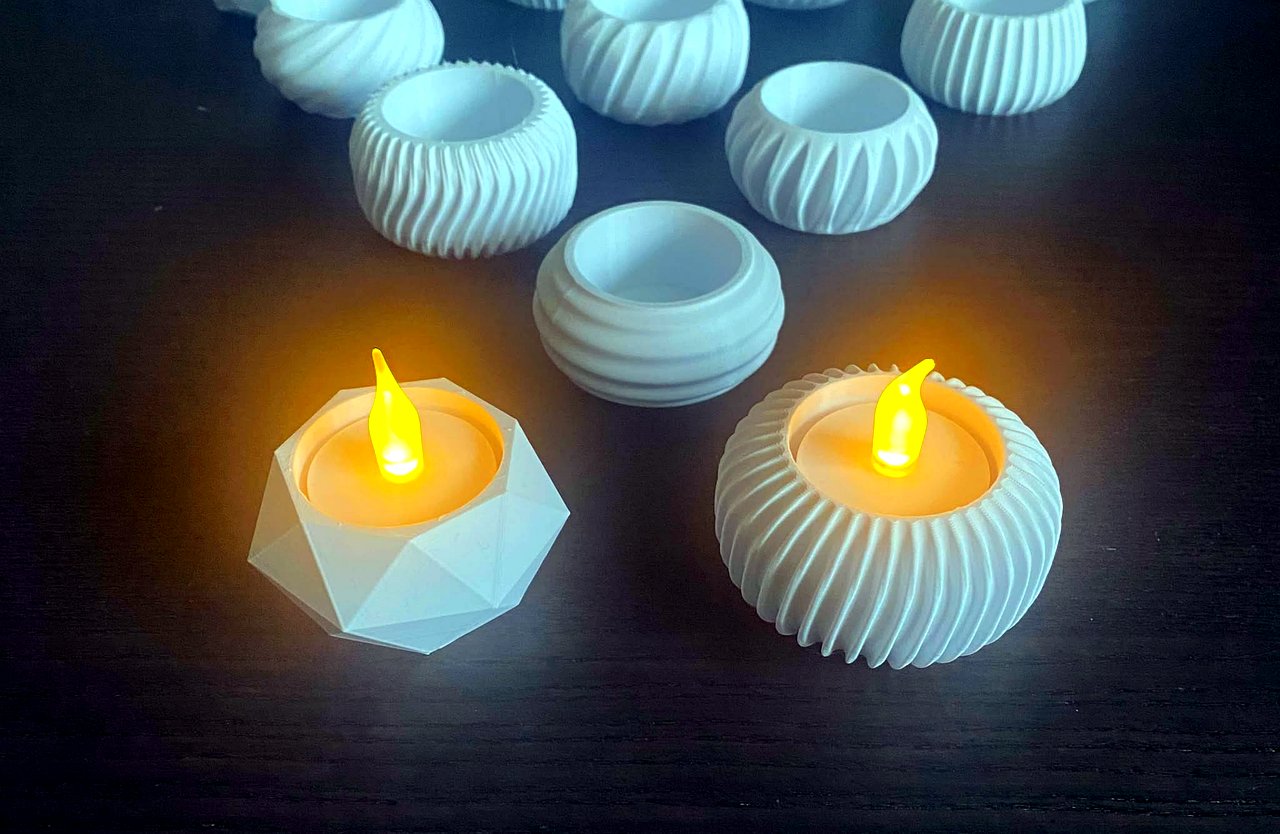 Close-up shot of a small modern 3D printed Diwali desk lamp diya, delicate parametric lattice pattern, warm internal LED illumination, neon teal and violet shadows on dark surface, clean maker product photography.